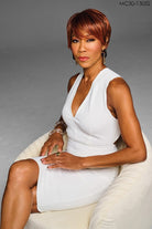 Model is wearing Kessie wig by Kim Kimble in MC30-130SS Cherry Cola | Front Sitting down 