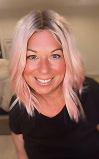 Person with pink hair wearing a black top indoors