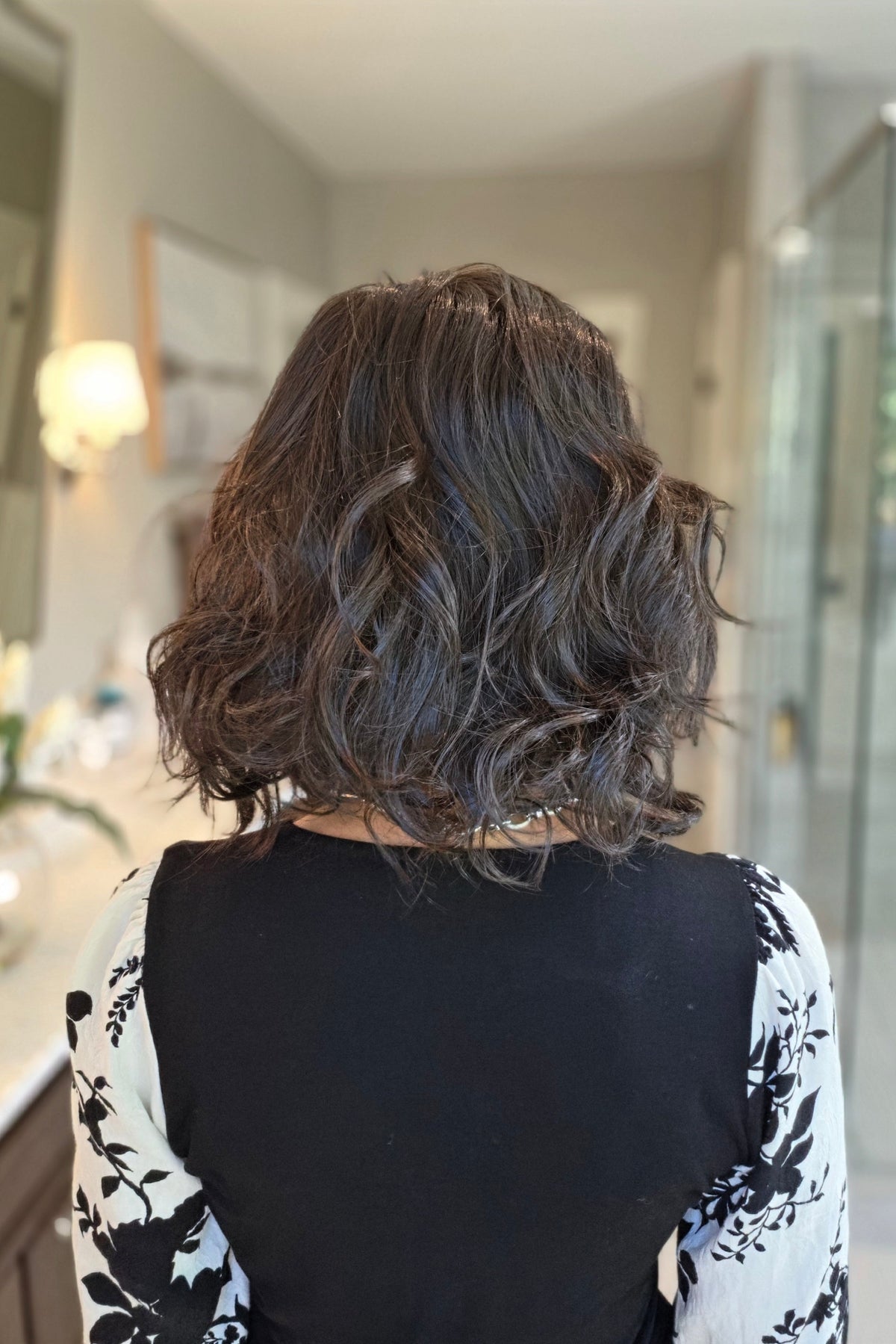 A woman with shoulder-length dark brown wavy wig (Lacy Lite by Jon Renau in 4).