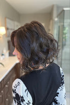 A woman with shoulder-length dark brown wavy wig (Lacy Lite by Jon Renau in 4).