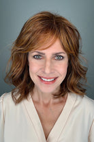A woman with a shoulder-length wavy red wig with bangs (Lively by Gabor in Medium Red).