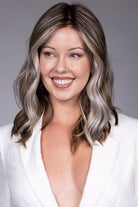 Magnolia by Belle Tress shoulder-length wavy wig with a center part and bright money piece highlights.