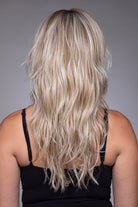 Back view of a long, blonde highlighted shag wig with textured, layered waves and a natural, voluminous finish.