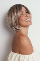 Maggie synthetic lace front bob wig with tousled blonde layers and a natural mono part on a smiling model.