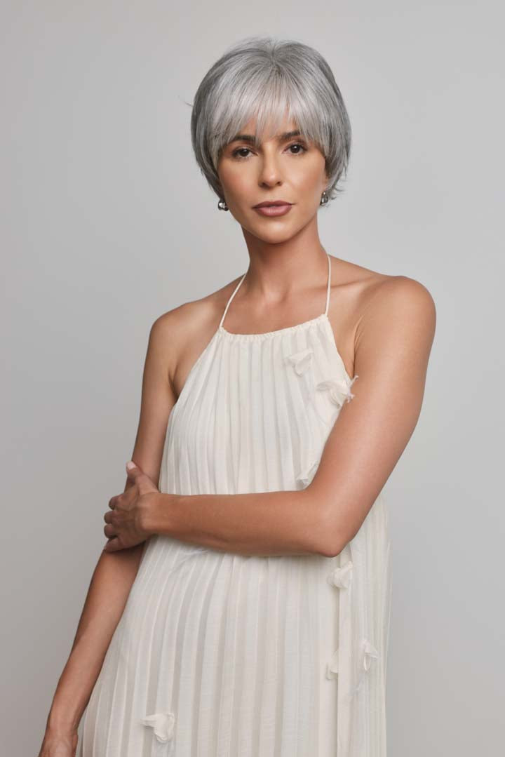 Model wearing a silver-grey Mio by Noriko short, layered synthetic pixie wig with a lace front and soft fringe.