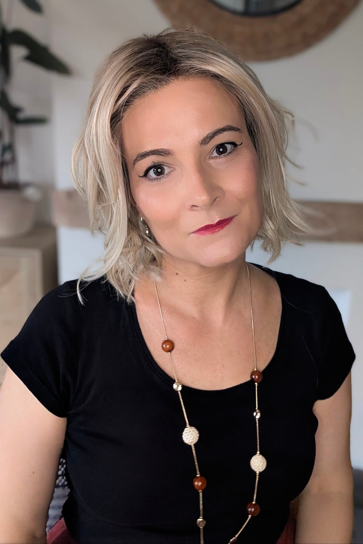 A woman with short blonde wavy bob wig (Naples by Belle Tress in color Crushed Almond Blonde R).