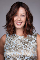 Orchid by Belle Tress shoulder-length wavy bob wig with a center part and auburn money piece highlights.