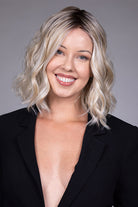Peony by Belle Tress shoulder-length blonde wavy bob wig with a center part and money piece highlights.