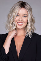Peony by Belle Tress shoulder-length wavy blonde bob wig with a center part and face-framing money piece highlights.