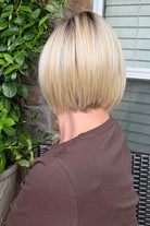 A woman with a chin-length blonde bob wig (River by PUSH Hair in Biscotti Blonde R).