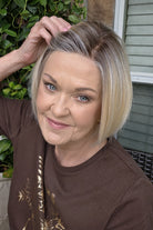 A woman with a chin-length blonde bob wig (River by PUSH Hair in Biscotti Blonde R).