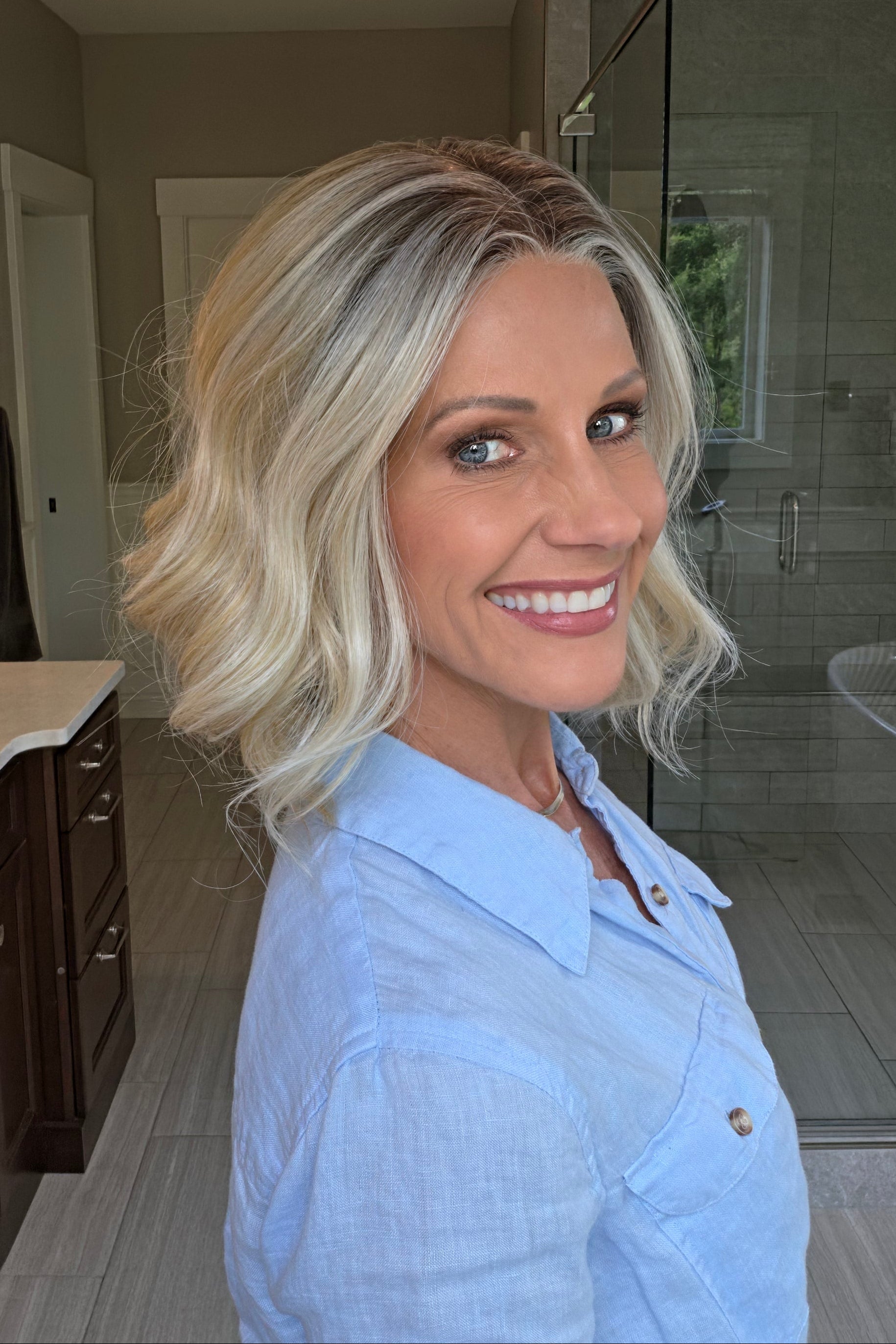 Woman wearing shoulder length curly blonde wig (Brielle by PUSH Hair in color Golden Champagne R)