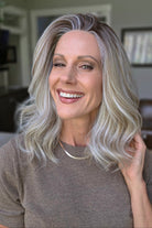 A smiling woman with shoulder-length wavy blonde wig (Keeley by PUSH Hair in color Champagne Blonde R).