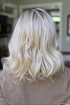 A smiling woman with shoulder-length wavy blonde wig (Keeley by PUSH Hair in color Champagne Blonde R).