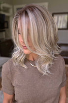 A smiling woman with shoulder-length wavy blonde wig (Keeley by PUSH Hair in color Champagne Blonde R).