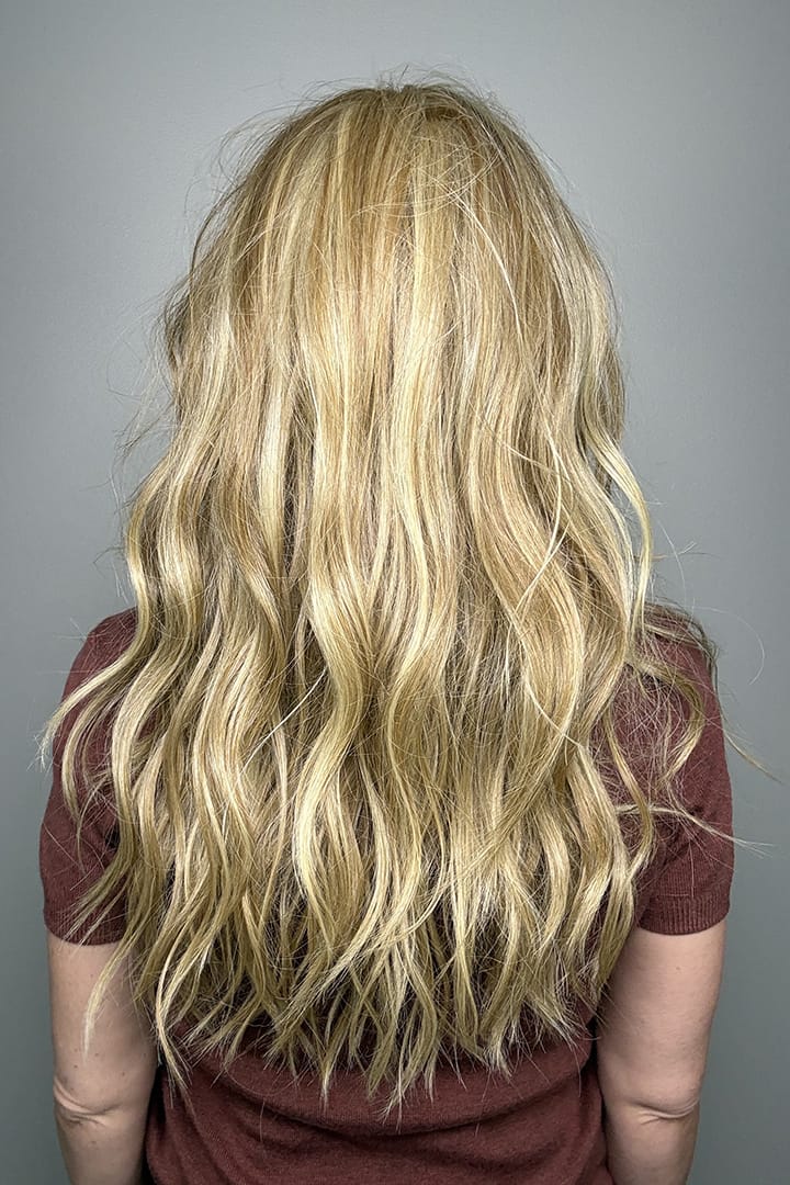 Woman with long blonde wavy wig (Posh Wavez by Rene of Paris in color Creamy Toffee) back