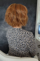 Woman wearing chin length bob with bangs (Rene of Paris' Rosanna in color Autumn Sunrise) back