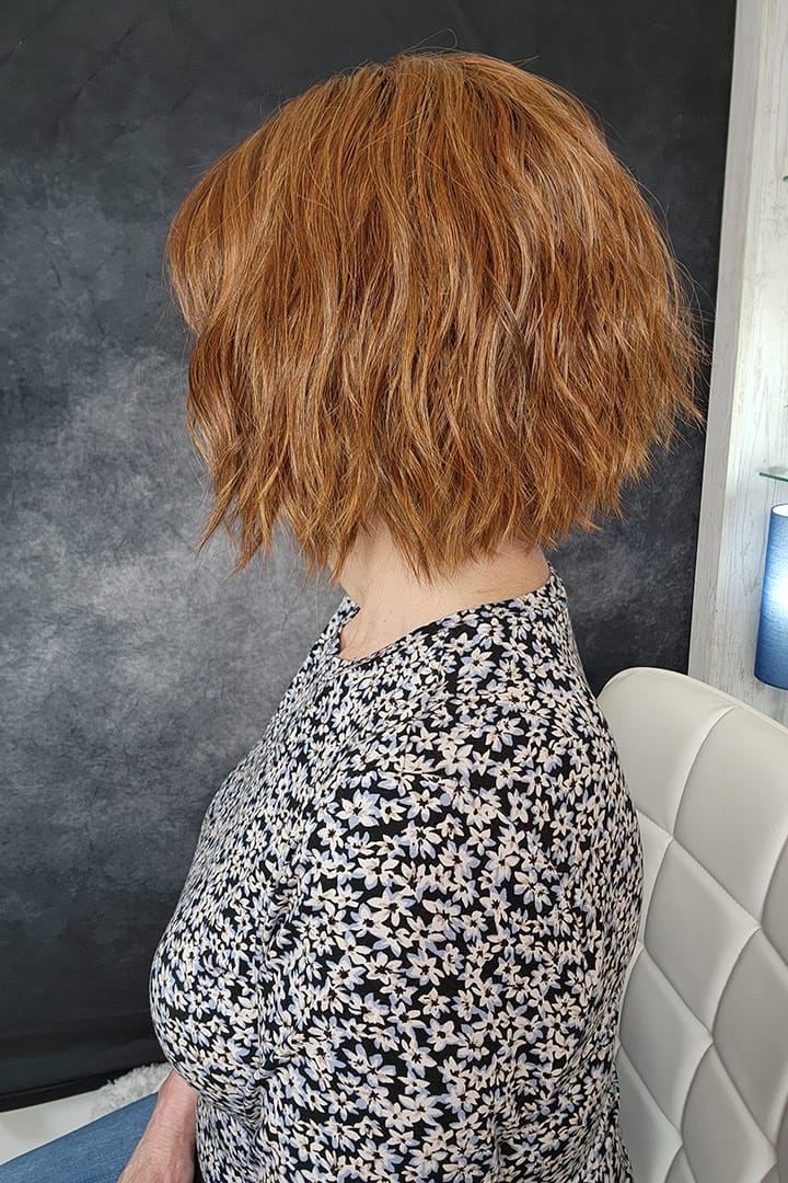 Woman wearing chin length bob with bangs (Rene of Paris' Rosanna in color Autumn Sunrise) side