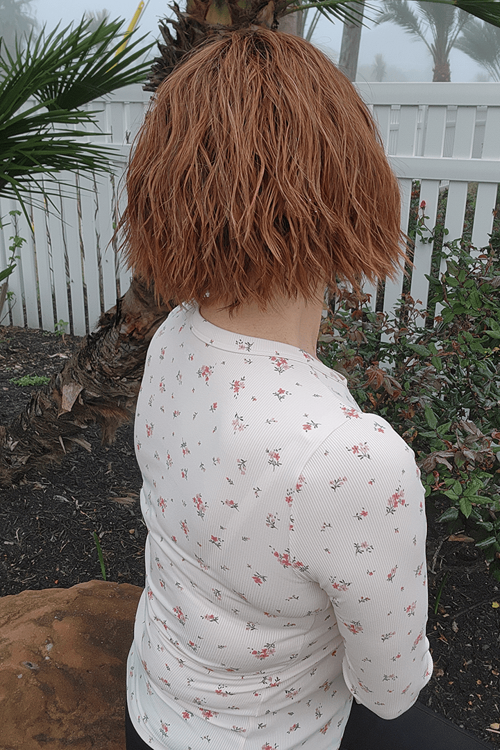 Woman wearing chin length bob with bangs (Rene of Paris' Rosanna in color Autumn Sunrise) back