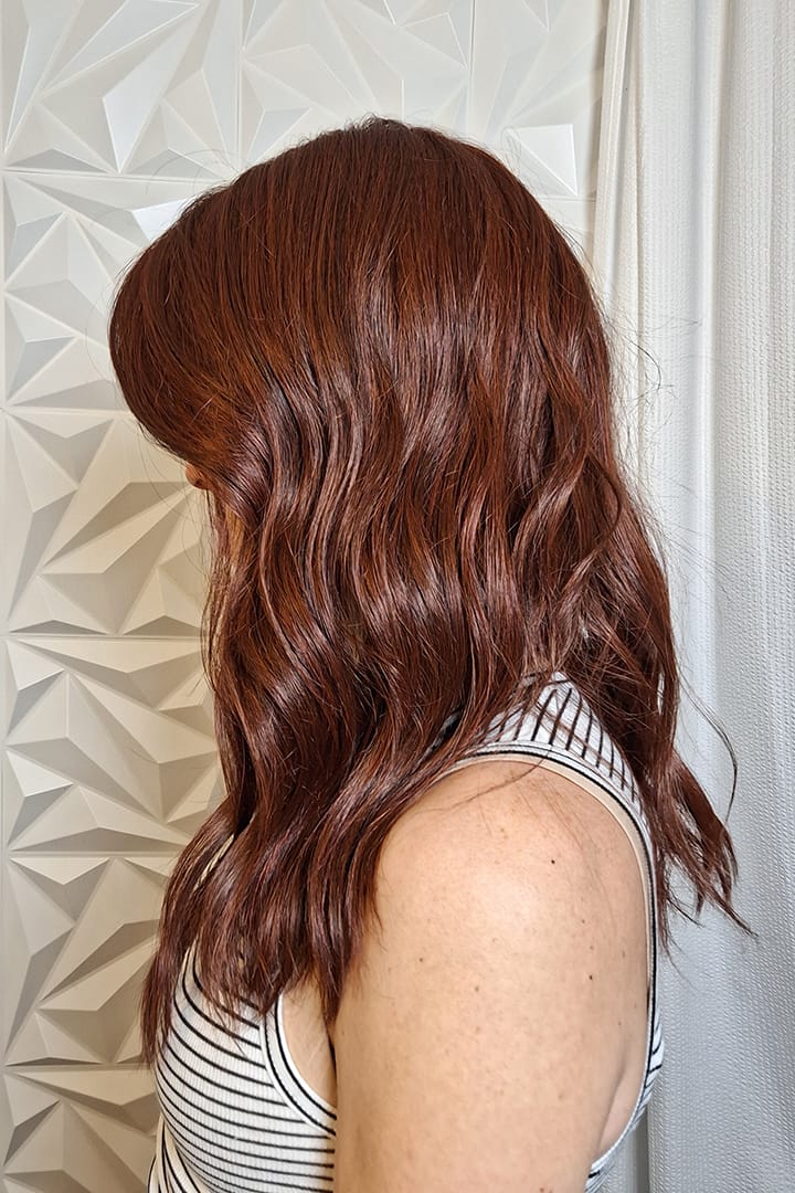Woman with long wavy red wig (Decadent Diva by Raquel Welch in Deepest Ruby) side