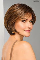 Woman with a stylish Raquel Welch Wig against a gray background