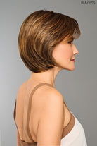 Woman with a styled Raquel Welch Wig against a gray background