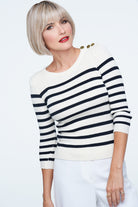 Woman wearing a black and white striped sweater against a white  background with a blonde wig