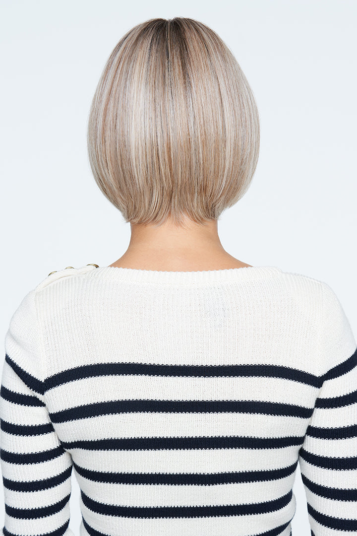 Woman wearing a striped sweater with a plain background, revealing back on blonde wig