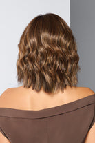 Back view of a brown, shoulder-length synthetic wig with soft, sculpted waves and a layered, textured finish.