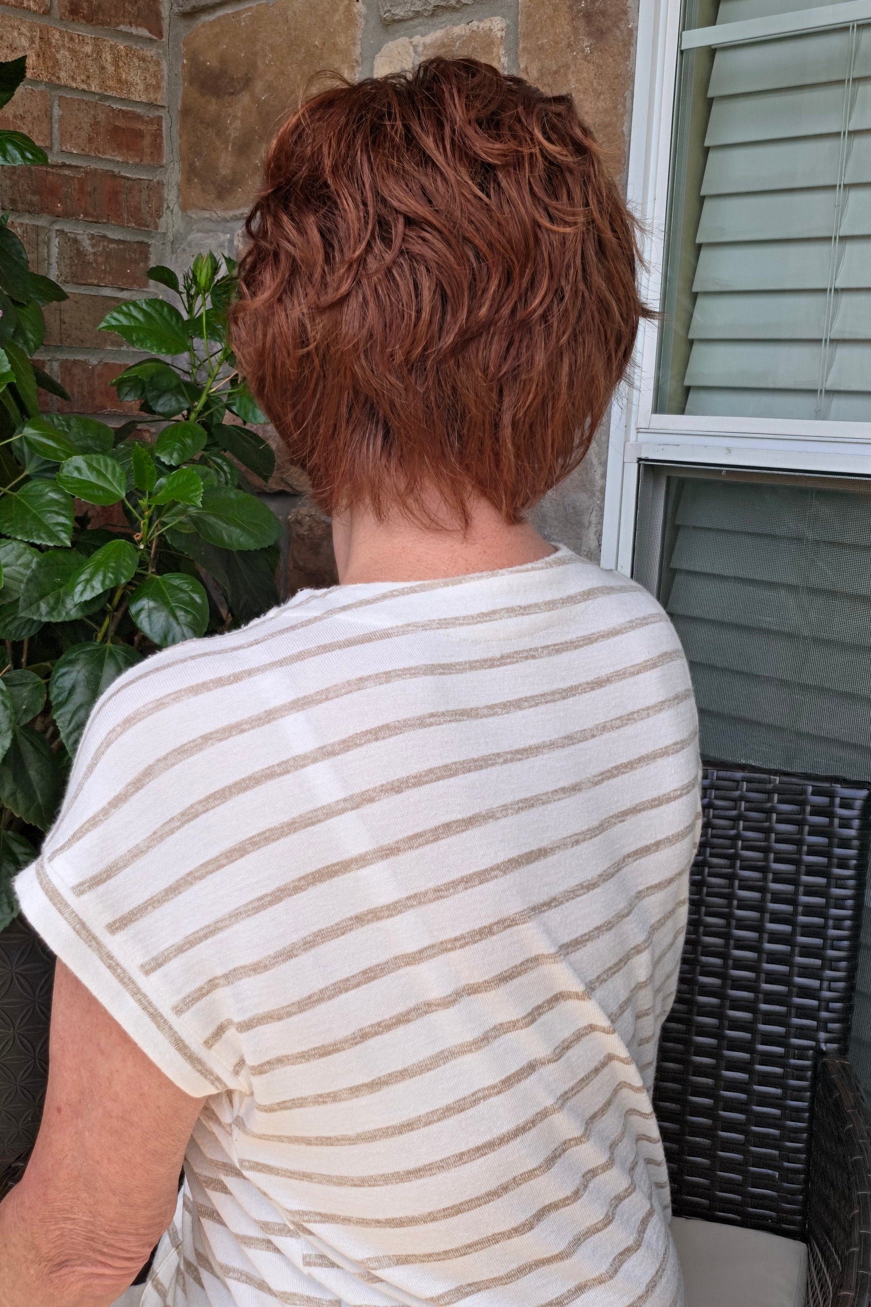 A woman with short reddish-brown hair wearing a white and beige horizontally striped short-sleeve top (Asha by Rene of Paris in color Cafe Rouge R).