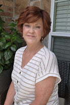 A woman with short reddish-brown hair wearing a white and beige horizontally striped short-sleeve top (Asha by Rene of Paris in color Cafe Rouge R).