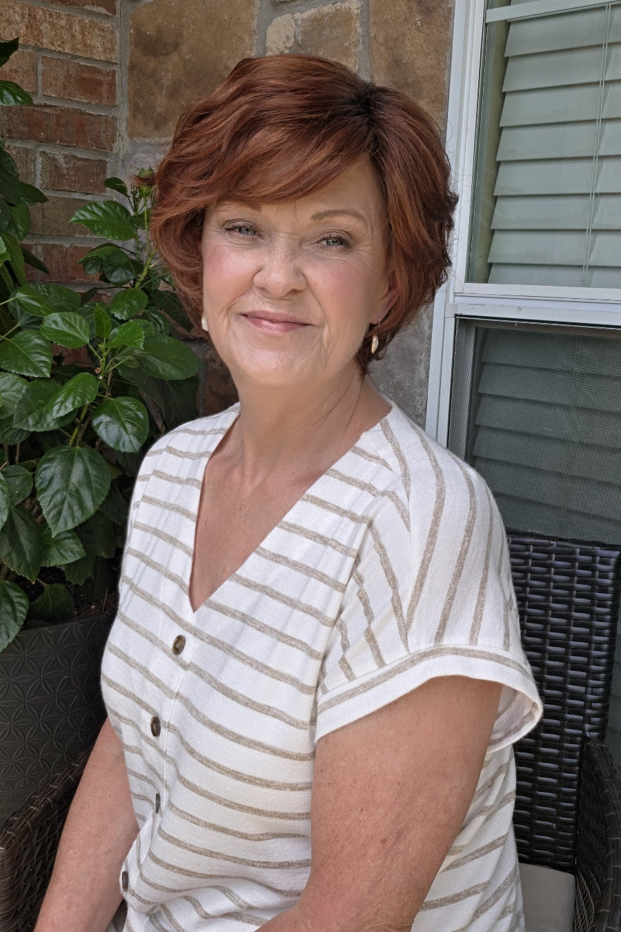 A woman with short reddish-brown hair wearing a white and beige horizontally striped short-sleeve top (Asha by Rene of Paris in color Cafe Rouge R).