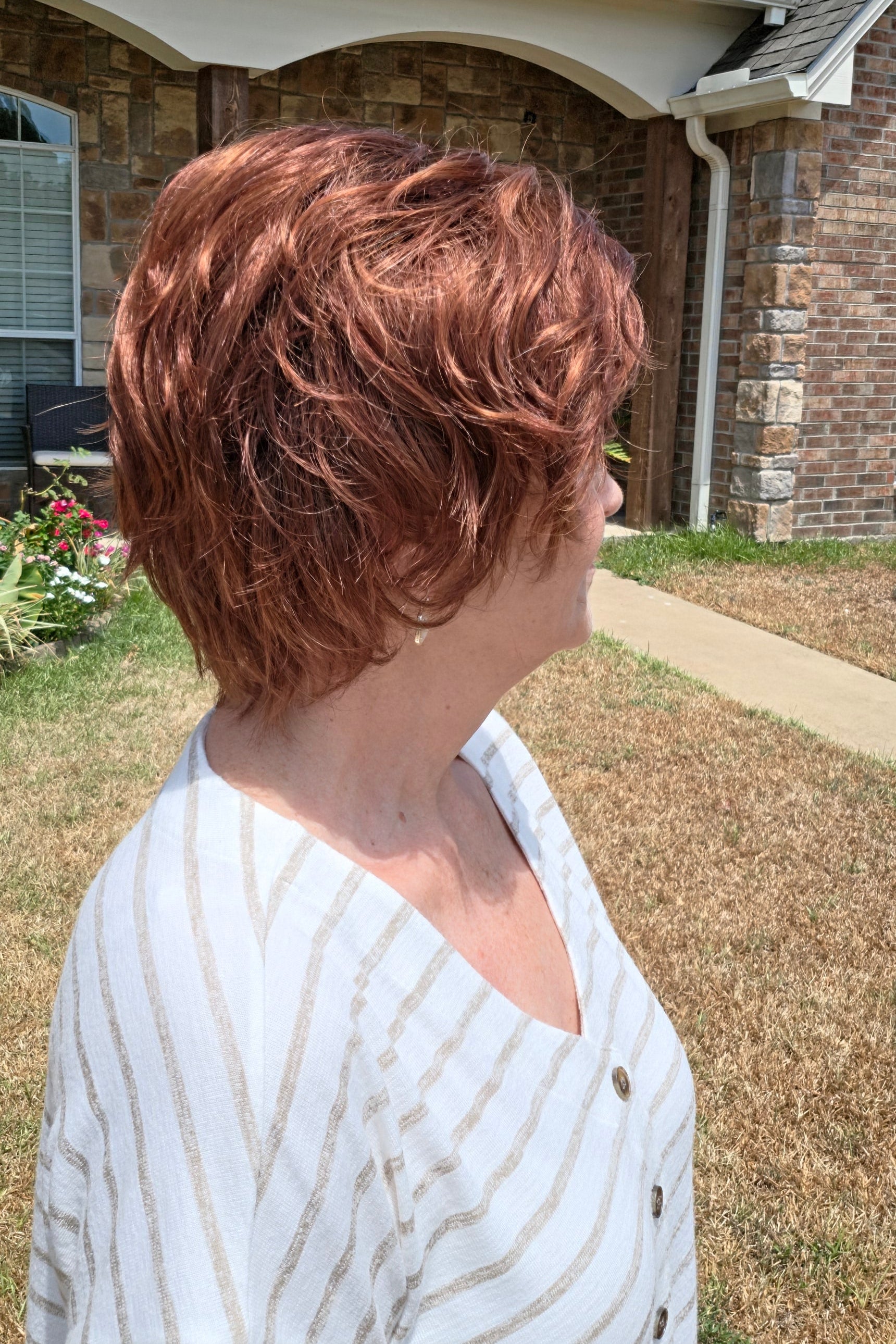A woman with short reddish-brown hair wearing a white and beige horizontally striped short-sleeve top (Asha by Rene of Paris in color Cafe Rouge R).