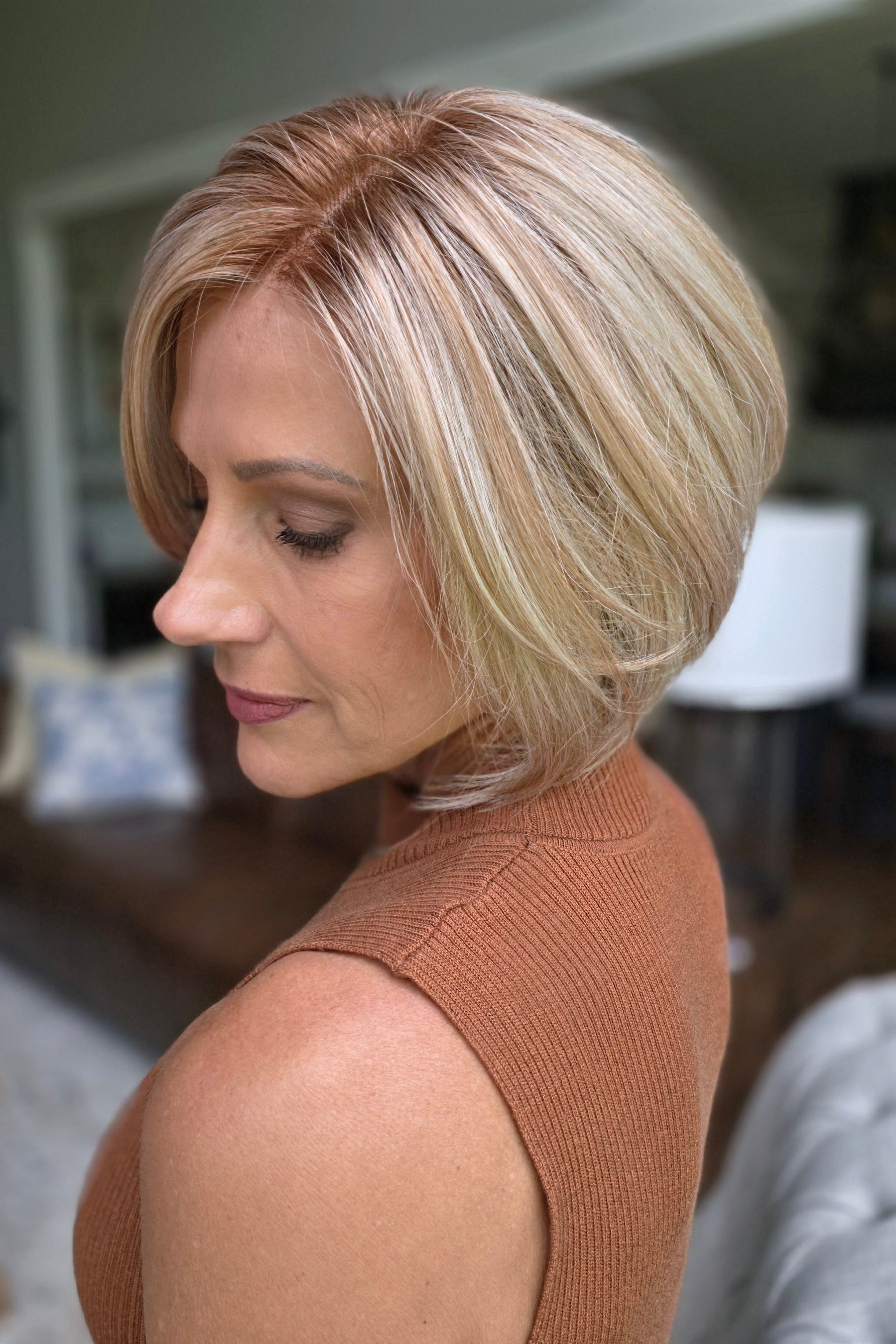 A woman with a short blonde bob hairstyle wearing a ribbed sleeveless rust-brown top (Maggie by Rene of Paris in Winter Oak Latte R).