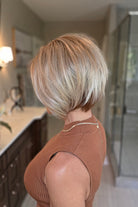 A woman with a short blonde bob hairstyle wearing a ribbed sleeveless rust-brown top (Maggie by Rene of Paris in Winter Oak Latte R).