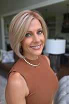 A woman with a short blonde bob hairstyle wearing a ribbed sleeveless rust-brown top (Maggie by Rene of Paris in Winter Oak Latte R).