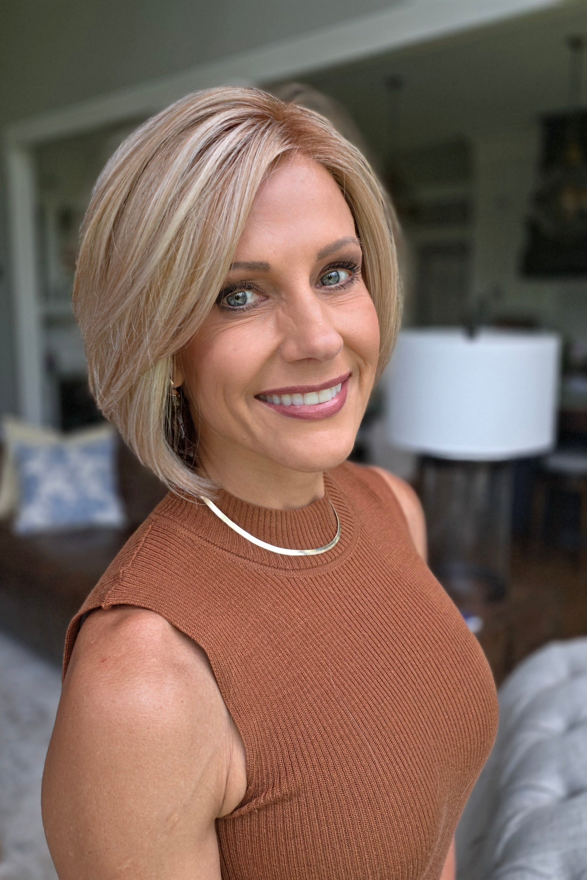 A woman with a short blonde bob hairstyle wearing a ribbed sleeveless rust-brown top (Maggie by Rene of Paris in Winter Oak Latte R).