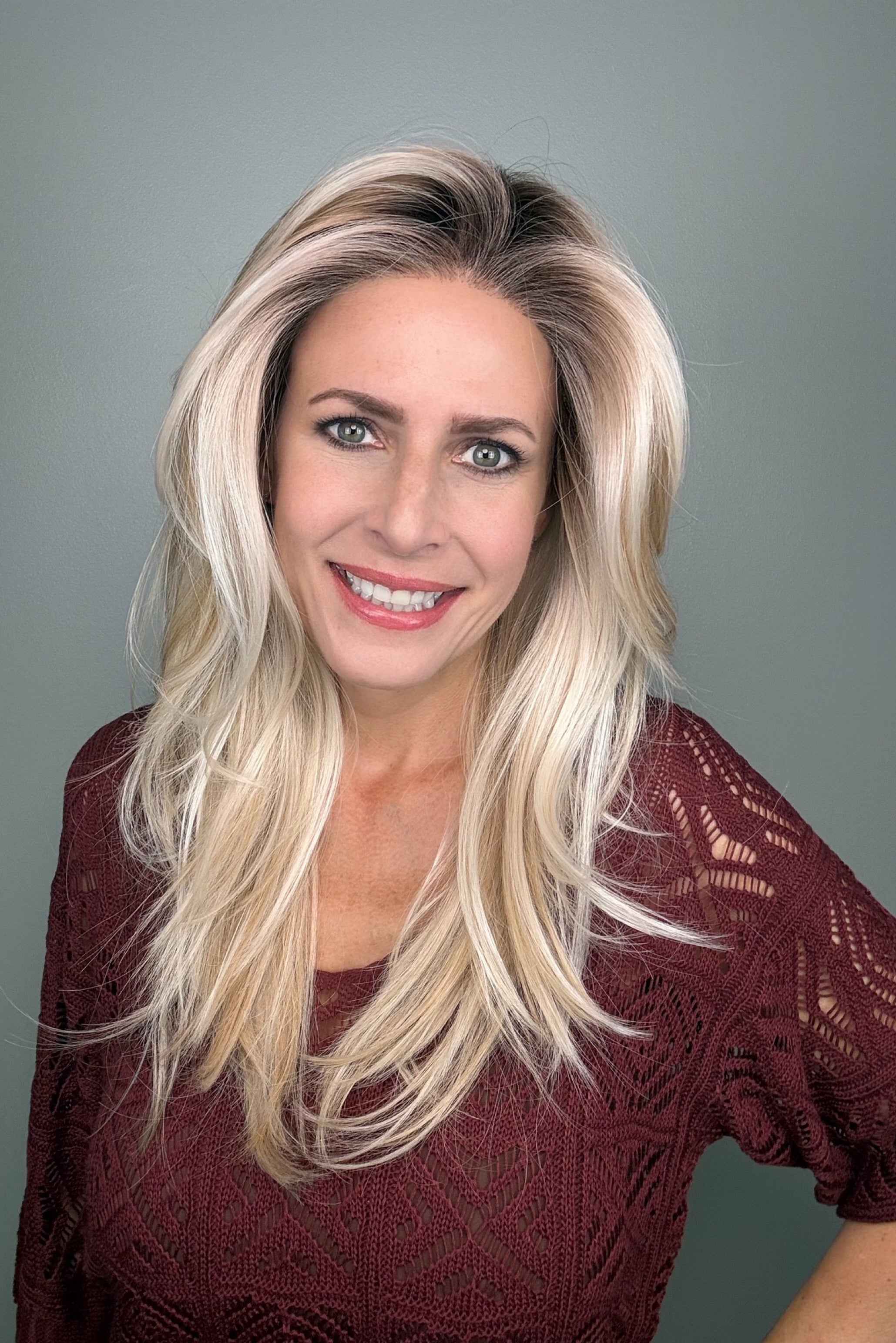Woman wearing a long layered rooted blonde wig (Sizzle by TressAllure in Sand and Sun Lighted)
