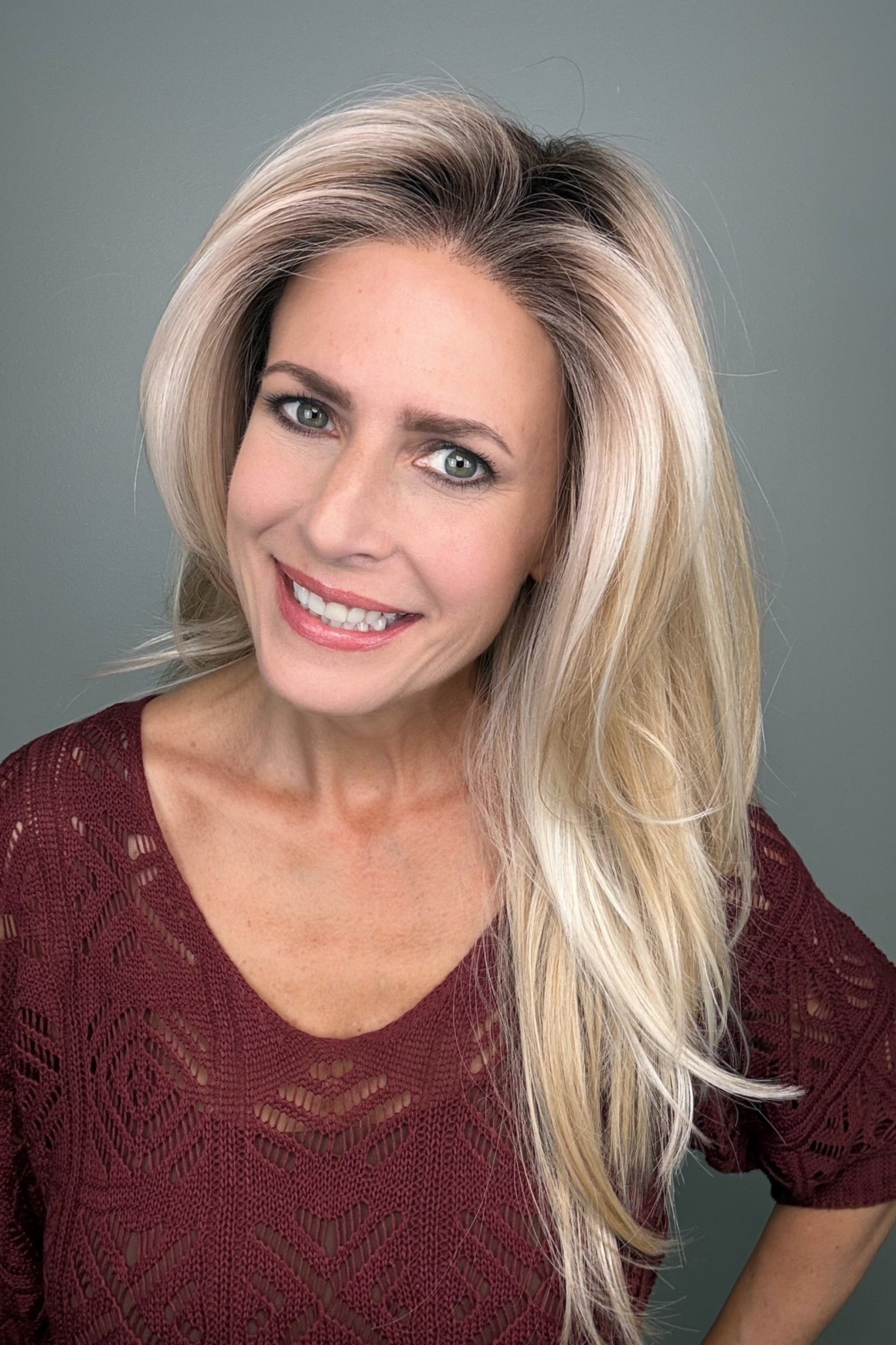 Woman wearing a long layered rooted blonde wig (Sizzle by TressAllure in Sand and Sun Lighted)