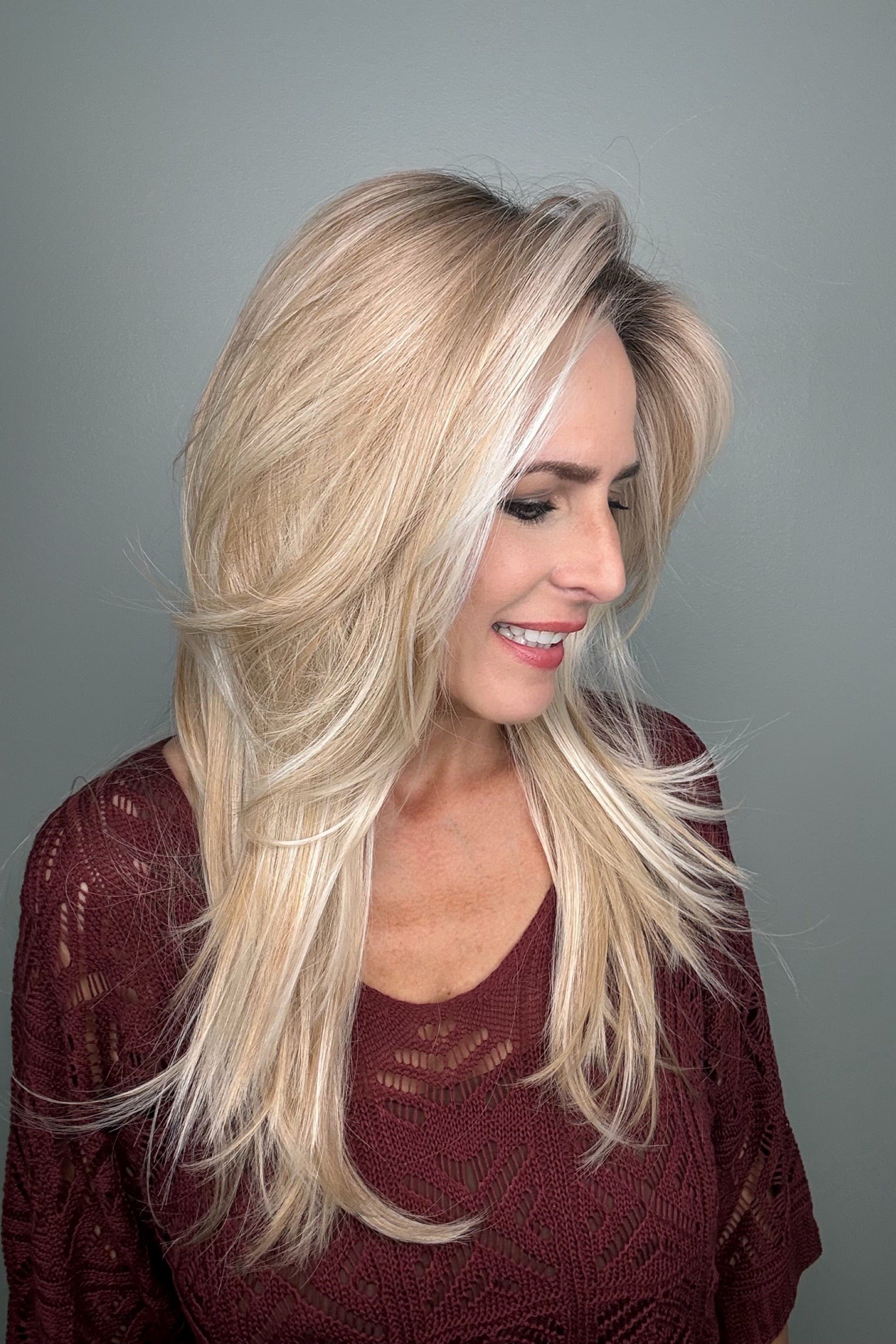 Woman wearing a long layered rooted blonde wig (Sizzle by TressAllure in Sand and Sun Lighted)