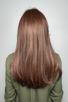 Woman wearing long layered wig with curtain bangs (Sleek Sophistication by Raquel Welch in color Copper Mahogany) back