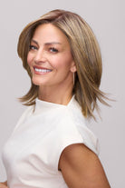 Woman wearing a mid-length, layered blonde synthetic wig with a natural lace front and sleek finish.