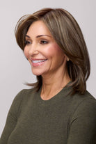 Mid-length layered brown wig with face-framing highlights and a natural lace front on a smiling woman.