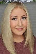 Woman with blonde hair and makeup wearing a maroon shirt.