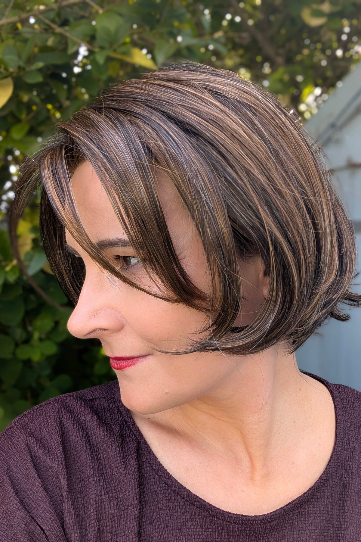 A woman with a short brown bob wig with subtle side-swept bangs (Stand Out Style by Gabor in color SS Hazelnut).