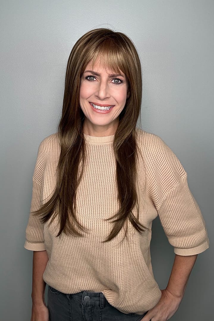 Woman wearing long brunette wig with bangs and highlights (Stevie by Amore in Honey Wheat)