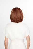 Woman wearing The Better Half synthetic wig by TressAllure in color 33/32/R4 with whit top and white background | Back view. 