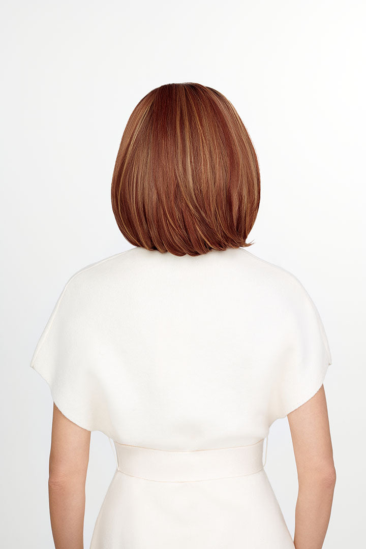 Woman wearing The Better Half synthetic wig by TressAllure in color 33/32/R4 with whit top and white background | Back view. 