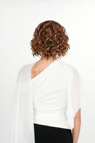 Woman wearing She's Like the Wind synthetic lace front wig by TressAllure in color 17/23/R8 with a white top and white background. Back view.