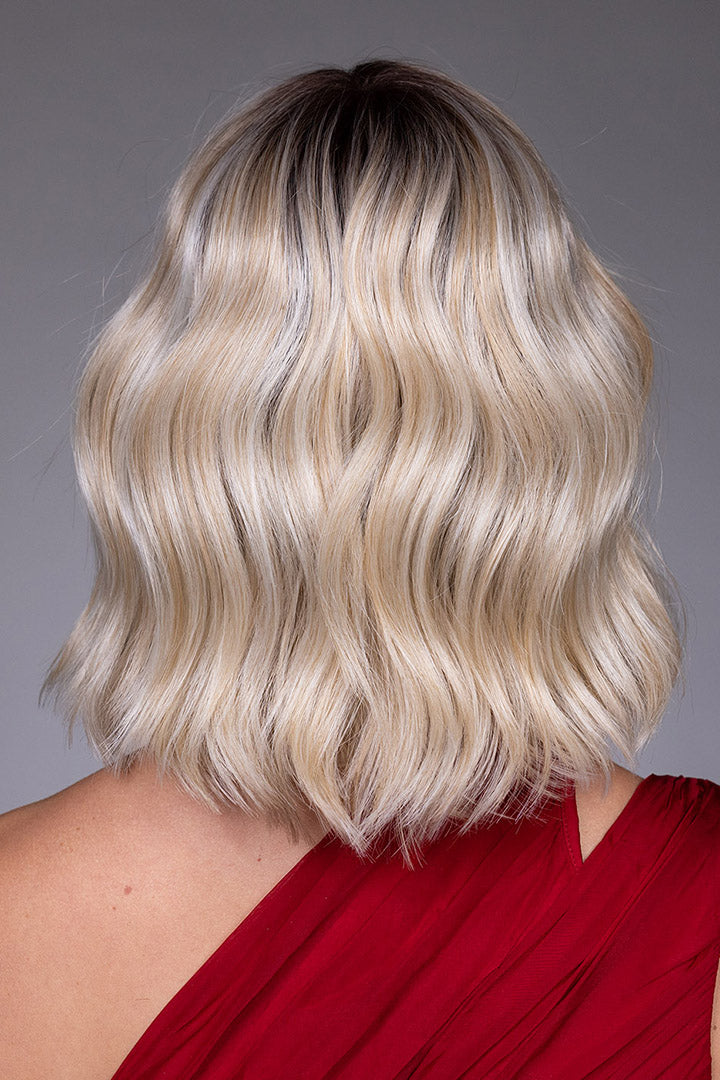 Back view of a blonde, wavy chin-length bob wig with dark roots and heat-friendly synthetic fibers.